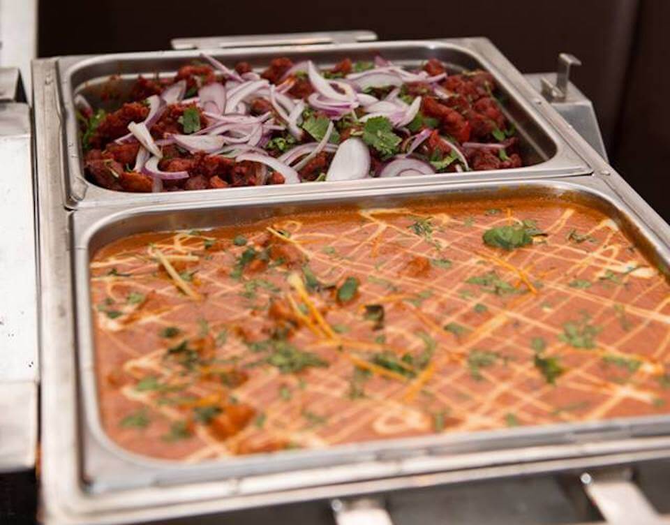 Chafing dishes of chilli chicken and butter chicken set up on a Dosa Hut catering buffet